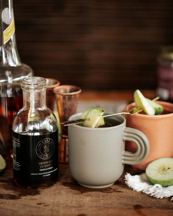 Close up of Kvas Northern Maple Old Fashioned Simple Syrup and Old Fashioned Hot Cider in ceramic mug