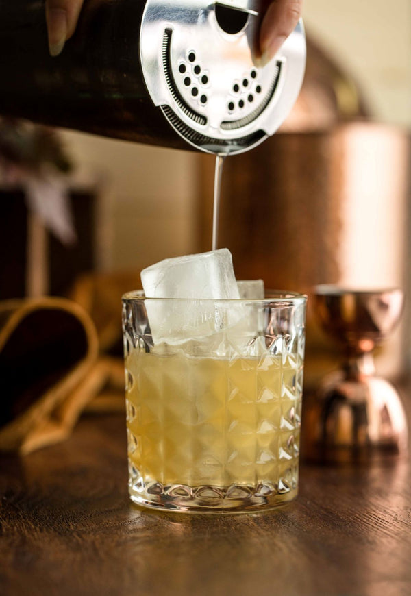 Henicillin cocktail made with Kvas Ginger Wildflower Simple Syrup being poured into glass