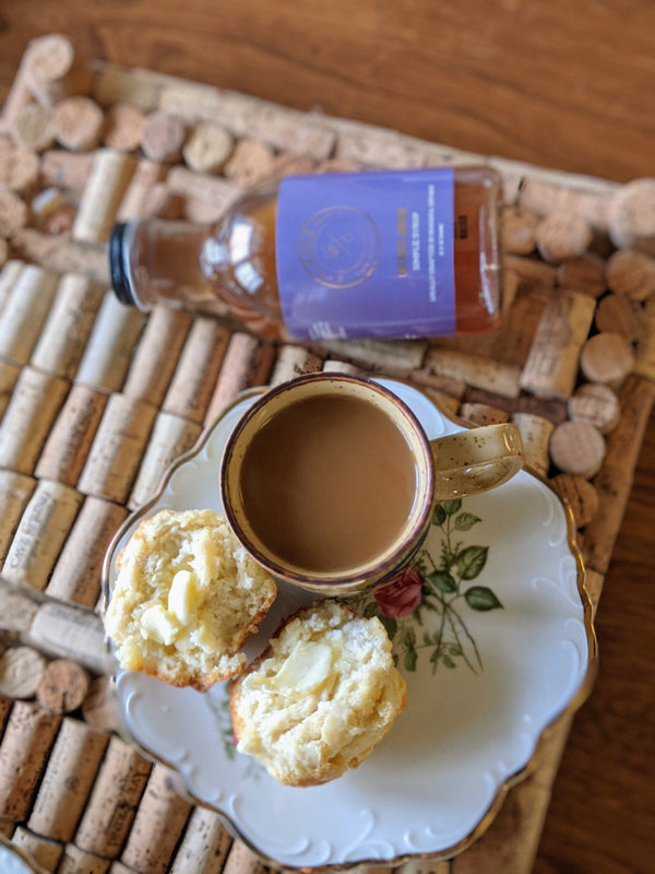 Overhead shot of lavender lemon scones and coffee next to Kvas Lavender Jasmine Simple Syrup bottle
