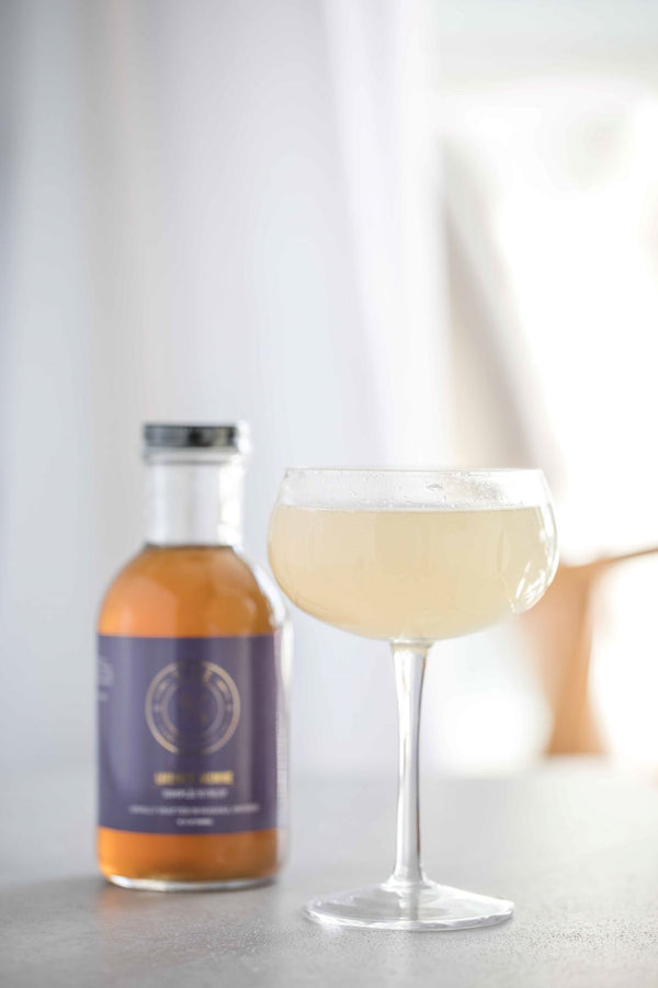 Closeup of The Bench 75 cocktail and bottle of Kvas Lavender Jasmine Simple Syrup