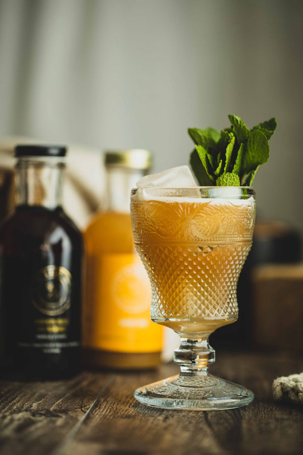 Close up of Apples to Apples Non-Alcholic cocktail with Kvas syrups beside