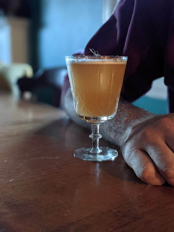 Person sitting at bar with Rococo Sour made with Kvas Whisky Sour Syrup