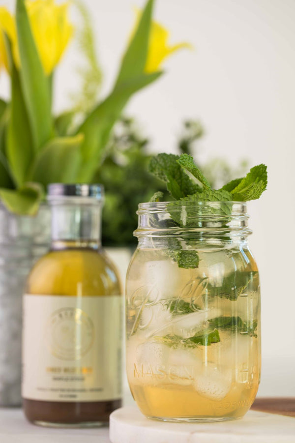 Closeup of Riesling Mojito cocktail next to bottle of Kvas Ginger Wildflower Simple Syrup