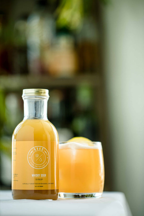 Close up of classic whisky sour cocktail and Kvas Whisky Sour Syrup bottle