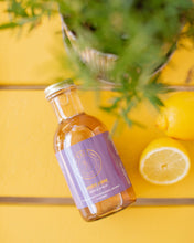 Load image into Gallery viewer, Staged closeup shot of Kvas Lavender Jasmine Simple Syrup next to lemons and plant in background